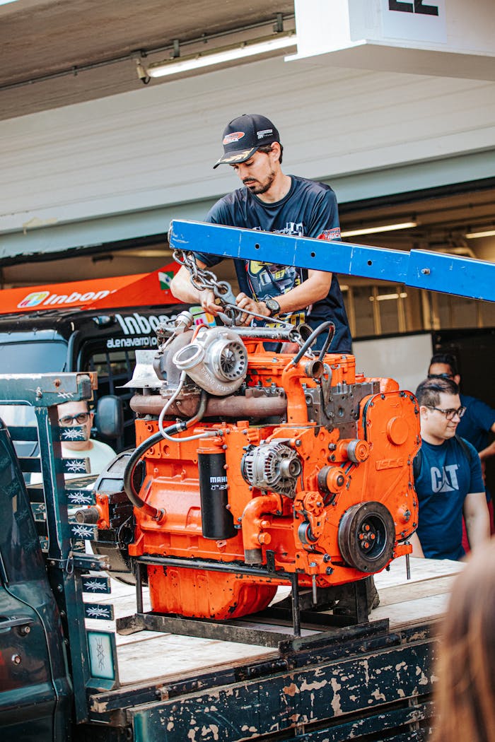 Home Skilled mechanic working on a large orange engine with a hoist, outdoors in São Paulo.